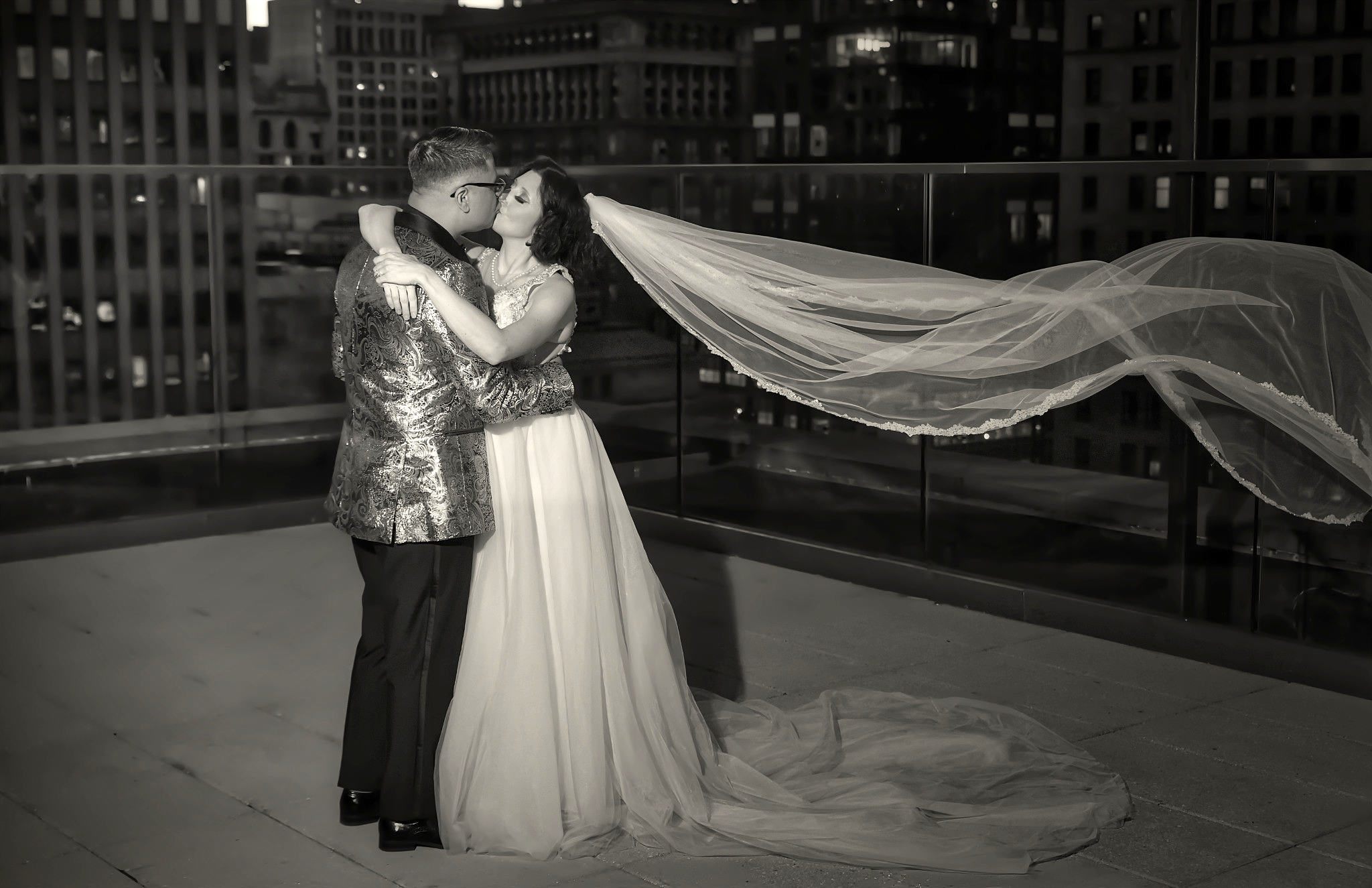 Couple kissing on rooftop — veil flowing in the wind